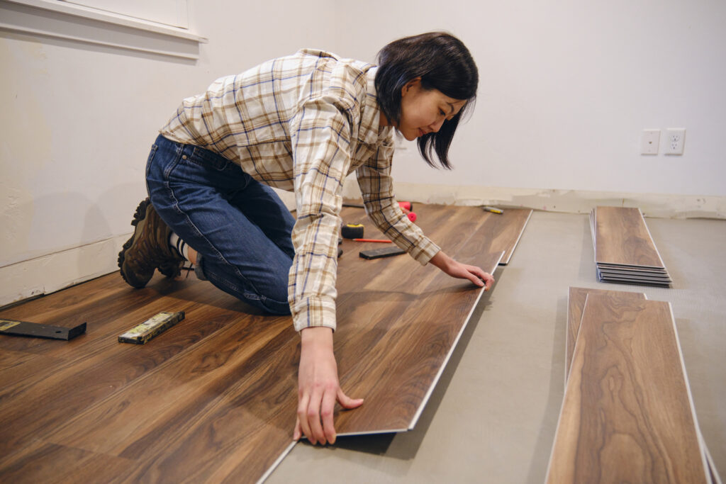 DIY home repair. A woman installing laminate flooring in her home.