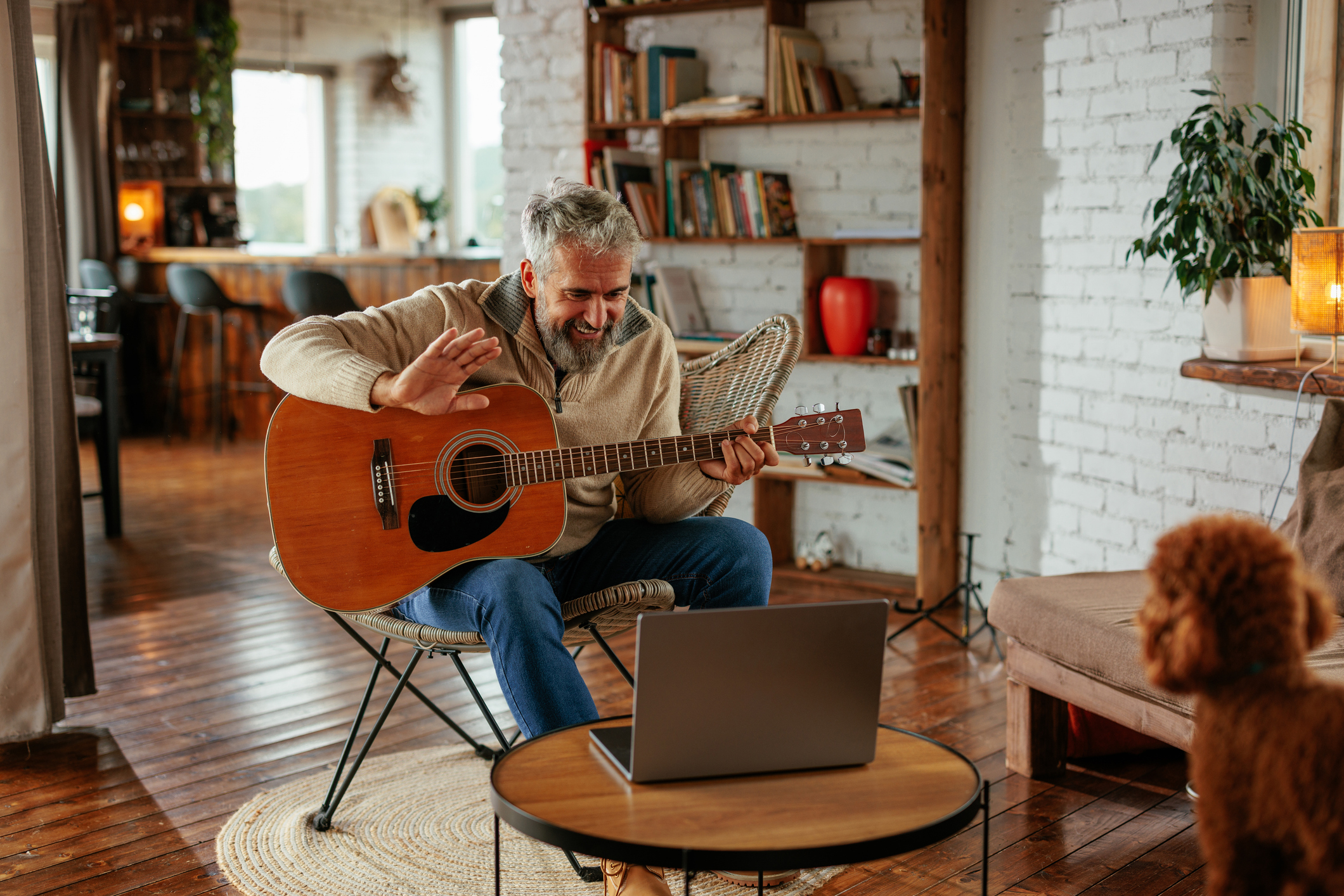 music lessons. A mature Caucasian man is at home having an online guitar class with his mentor on the laptop.